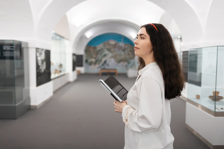 Side view of pretty young caucasian girl student visiting museum exhibition. Concept of cultural education and Museum's Day.の写真素材