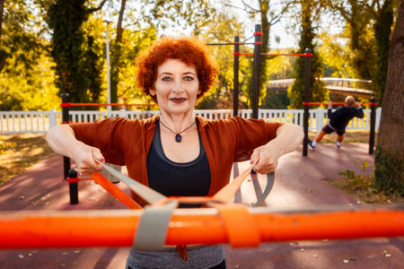 Training in park. Portrait of adult smiling Caucasian woman looking in camera does stretching with...