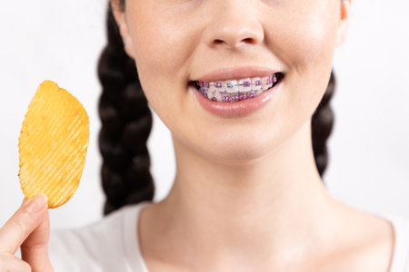 Close-up of young smiling woman refusing to hold potato chips. Concept of forbidden food during...