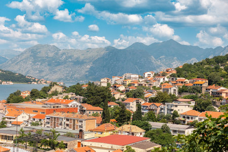 Landscape view of old town of Kotor, with red roofs and mountains and clouds in the background. Mediterranean resort city.の写真素材