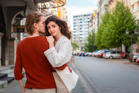 Back view of young Caucasian romantic couple man and woman embraced on street, arrange date. Valentine's Day. Copy space. Concept of relationship psychology.の写真素材