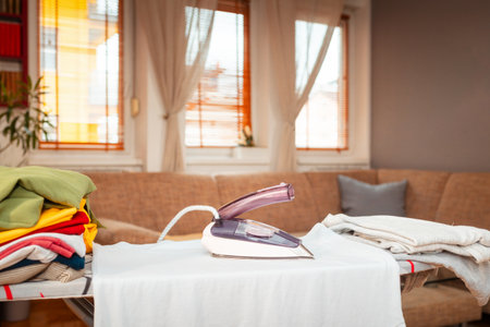 Iron is on t-shirt on ironing board. Concept of household fire danger with electric household appliances. Copy spaceの写真素材