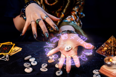 The fortune teller holds a rune with a luminous astrological circle above it in the palm of her hand. The concept of divination, astrology and predicting the future.の写真素材
