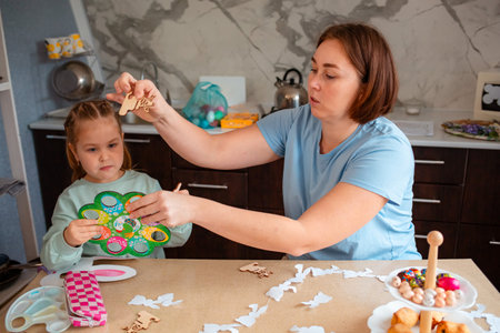 Mid shot of mother and a little daughter are preparing for the holiday by decorating eggs for the...