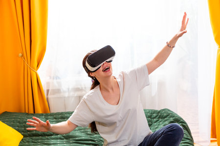 Portrait of woman sitting cross-legged on bed fully immersed in virtual reality, navigating future gaming experiences.の写真素材