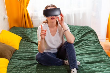 Female relaxing in a modern bedroom, enjoying innovative VR content. Top view.の写真素材