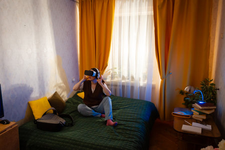 Caucasian woman tests immersive virtual reality equipment in bedroom. Leisure, technology use, and...