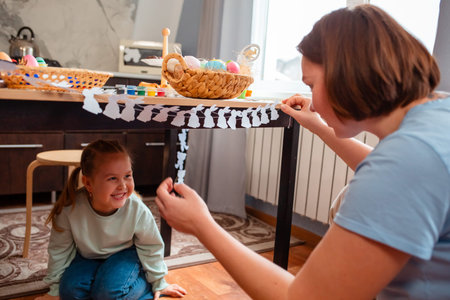 View from the shoulders of Caucasian mother decorates the home inside together with little happy daughter for the Easter spring holidayの写真素材