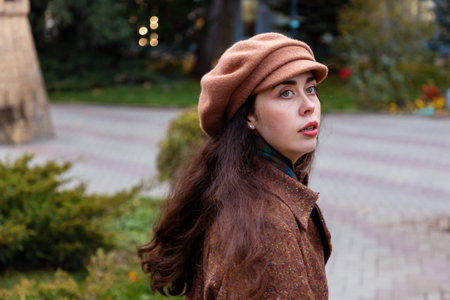 Young woman in elegant outerwear walks slowly through the quiet city, lost in personal thoughtsの写真素材