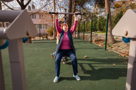 Elderly Caucasian woman training on a street gym in an urban park. Sport, wellness, and active...