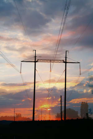 Electric lines against the sky painted by a sunsetの写真素材