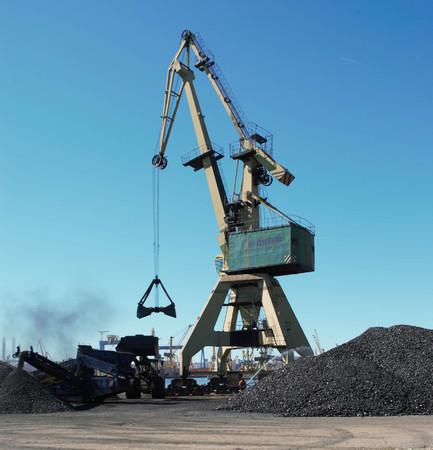 Conveyor belt with charcoal and a crane in the background with blue sky - loading ships in port / wagons / transport / industry / Constanta portの写真素材