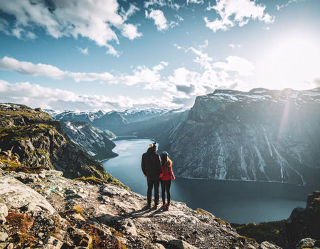 Couple standing on top of a mountain and looking at fjord in Norwayの素材
