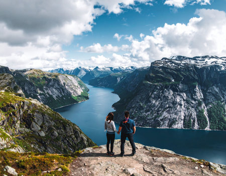 Tourism vacation and travel. Couple standing on the edge of a cliff and looking at the fjord. Norway Scandinavia.の素材