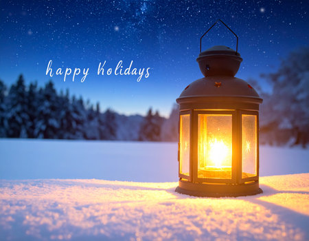 Christmas greeting card with a glowing lantern in the snow in the mountainsの写真素材