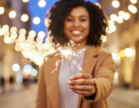 smiling african american woman with sparkler on city streetの素材