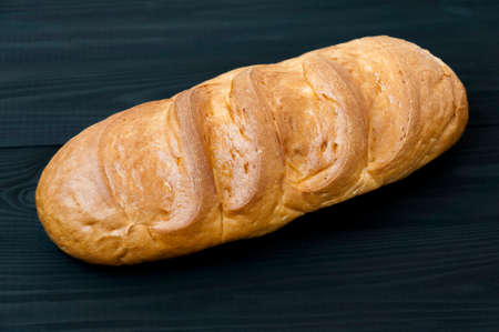 Bun of wheat bread on white black wooden table