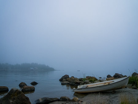 Rowing boat in fog by Bottenviken sea in Norrfjarden, Nordmaling, Swedenの写真素材