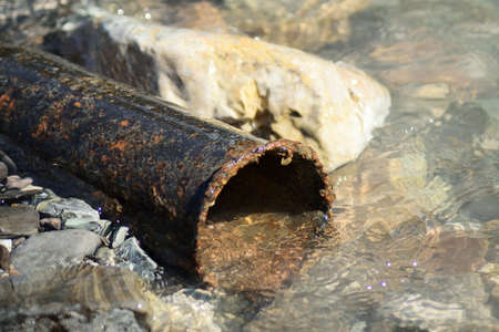 old rusty pipe flooded by river water