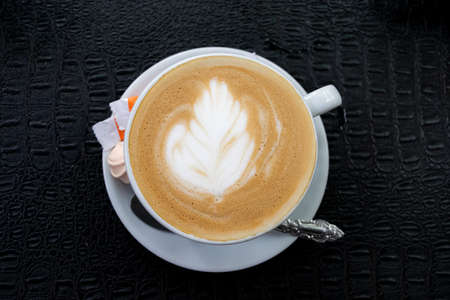 cappuccino with a flower pattern in a white cup on a black backgroundの写真素材