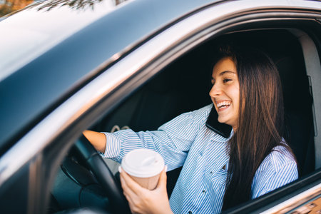 Woman driving car with coffee in her handの写真素材
