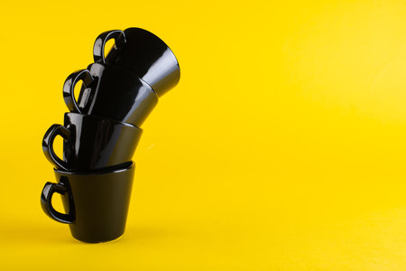 Black cups on a yellow background. A tower of cups. Minimalismの写真素材