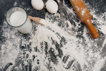 Ingredients for pastries: flour, eggs, milk against a dark backgroundの写真素材