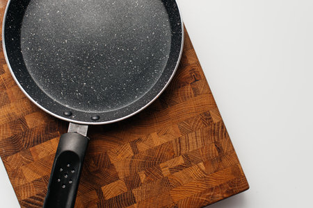 Empty pan on wood board. Empty marble coated iron pot