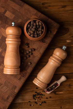 Pepper mill and whole pepper in wooden scoop on wood table.の写真素材