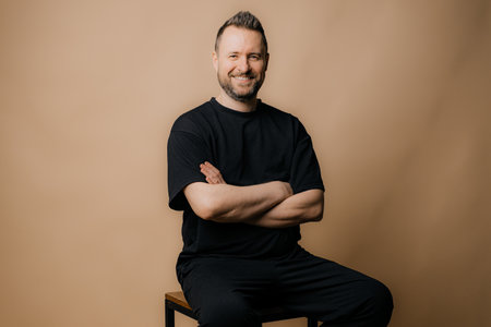 Portrait of smiling mature man standing on beige background.の写真素材