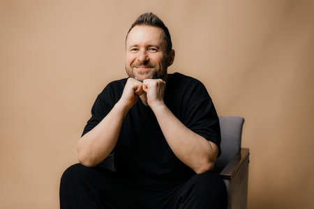 Portrait of smiling mature man standing on beige background.の写真素材