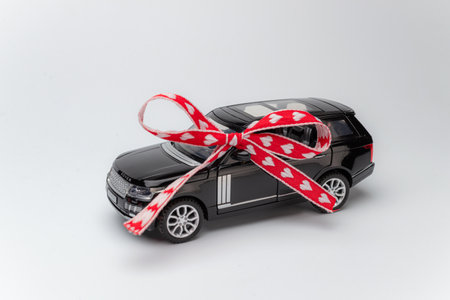 Concept of presenting new car. Black and modern automobile with red bow and ribbonの写真素材
