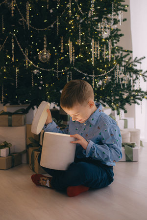 Portrait of curious boy looking inside big giftbox on Christmas eveningの写真素材