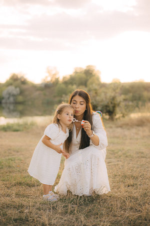 Happy young caucasian mother and toddler girl daughter smiling, summer park on background.の写真素材