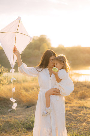 Happy young caucasian mother and toddler girl daughter smiling, summer park on background.の写真素材