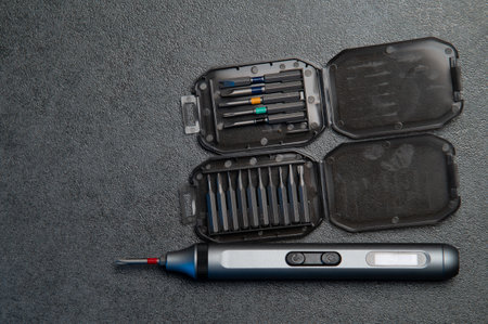 Electric rechargeable cordless mini screwdriver and set of different interchangeable bits in plastic case on a gray backgroundの写真素材