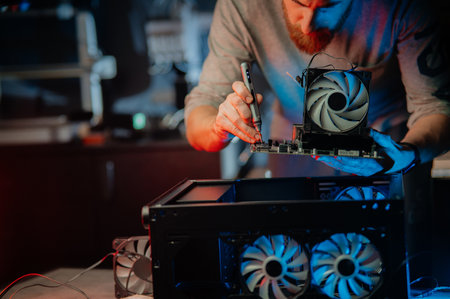 A man uses an electric screwdriver to upgrade and repair a desktop computer. Concept of modern...