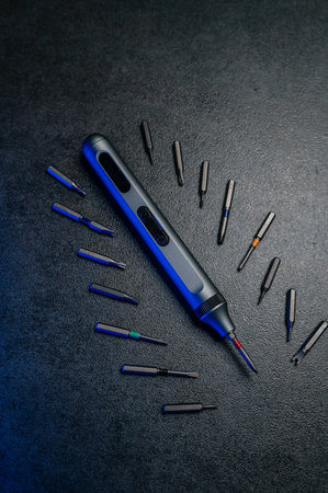 precision electric screwdriver and bits displayed on textured dark surface, product showcase for...