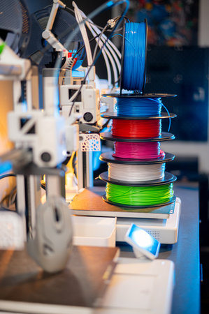 row of colorful 3d printing filament PLA material on environmentally friendly and recyclable paper cardboard spools on black carbon fiber background. modern FDM printer technology conceptの写真素材