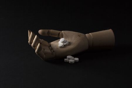 Wooden hand with pills on a black backgroundの写真素材