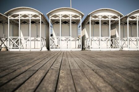 Background white sea bathing huts on wooden walkwayの写真素材