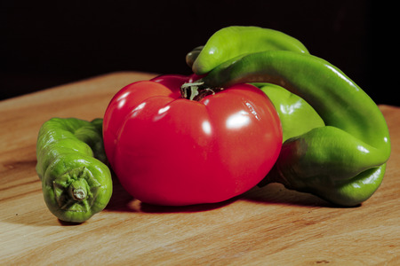Tomatoes cherry peppers on wooden cutting boardの写真素材