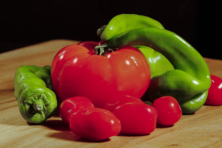 Tomatoes cherry peppers on wooden cutting boardの写真素材