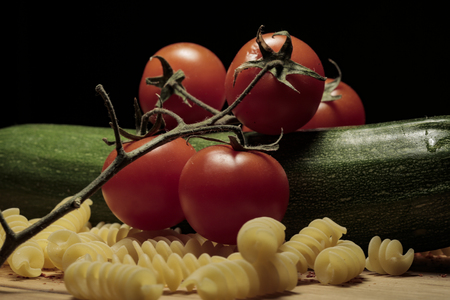 Zucchini spaghetti pasta tomatoes cherry chilli seeds on wooden cutting boardの写真素材