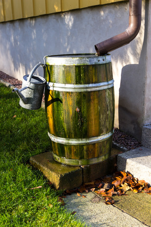 A barrel of rain water next to a houseの写真素材