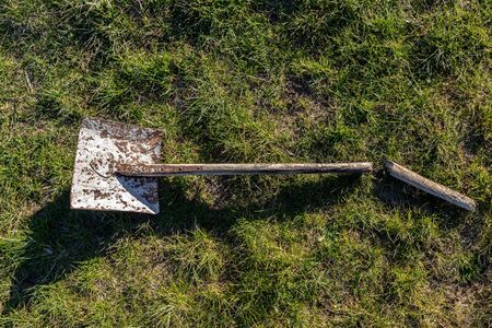 Broken spade lying on grass in the gardenの写真素材
