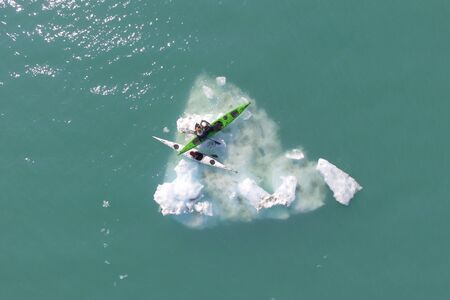 a pair of kayakers sits on an iceberg