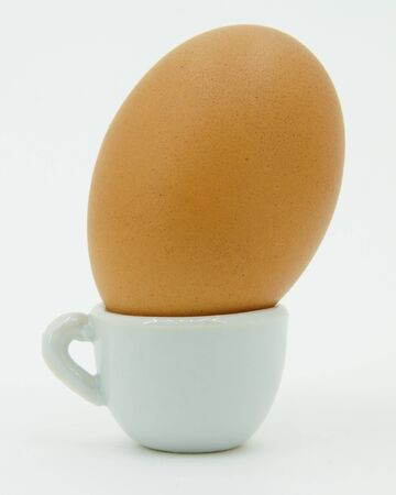 yellow egg in a small glass on a white backgroundの写真素材