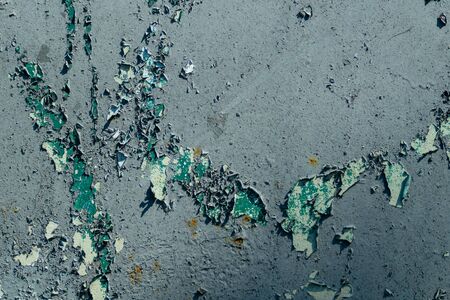texture on a gray wall with peeling paint from under which green is visible