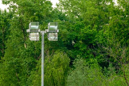 Lighting mast with four powerful lanterns for lighting large areas against a background of green...